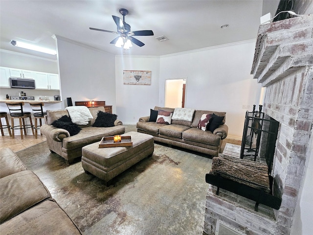 living area with ceiling fan, ornamental molding, a fireplace, and visible vents