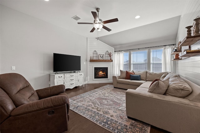 living room featuring a fireplace, lofted ceiling, visible vents, a ceiling fan, and wood finished floors