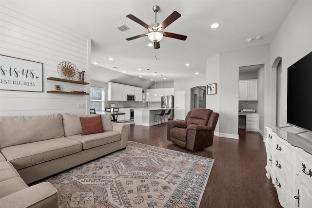 living area with arched walkways, dark wood-style flooring, a ceiling fan, and recessed lighting