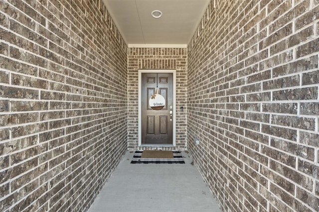 view of exterior entry featuring brick siding