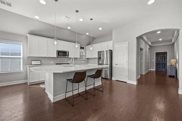 kitchen with appliances with stainless steel finishes, arched walkways, visible vents, and dark wood finished floors