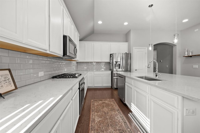 kitchen featuring arched walkways, appliances with stainless steel finishes, a sink, and white cabinetry