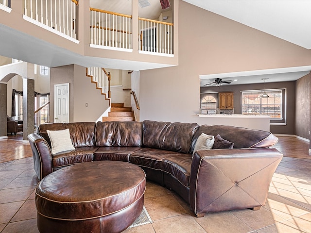 living area with ceiling fan, arched walkways, baseboards, stairway, and decorative columns