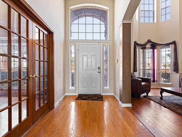 entryway featuring a towering ceiling, baseboards, and hardwood / wood-style floors