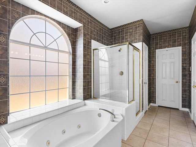 bathroom featuring a stall shower, a jetted tub, tile walls, and tile patterned floors