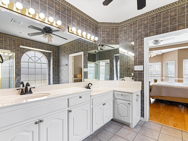 ensuite bathroom with tile patterned flooring, a sink, tile walls, and a ceiling fan