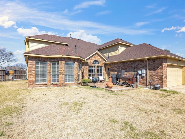 rear view of house featuring brick siding, a yard, a shingled roof, an attached garage, and fence