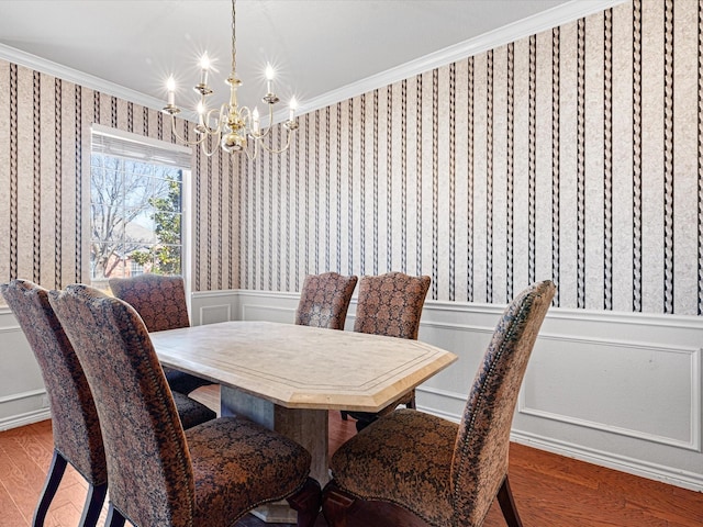 dining space with wallpapered walls, crown molding, a decorative wall, and wood finished floors