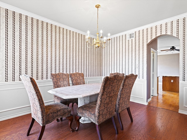 dining room with arched walkways, wood finished floors, visible vents, ornamental molding, and wallpapered walls