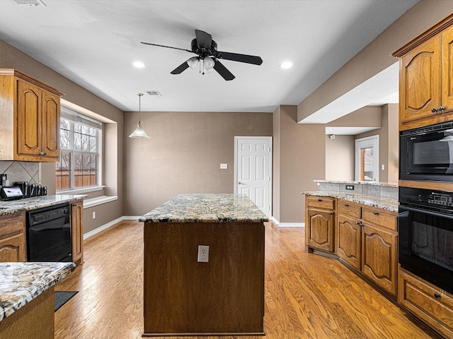 kitchen featuring light wood-style floors, a center island, visible vents, and black appliances