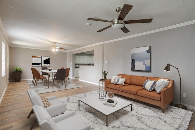 living area featuring ornamental molding, a ceiling fan, baseboards, and wood finished floors