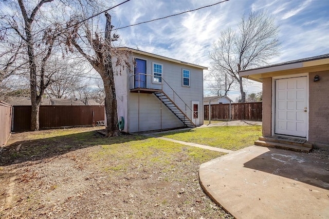 back of house featuring entry steps, a patio, a fenced backyard, stairs, and a yard