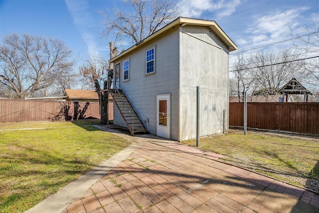 back of house featuring a fenced backyard, stairs, and a lawn