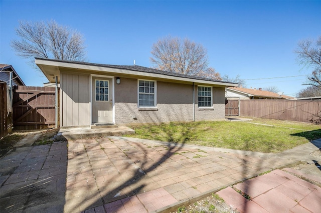 rear view of property featuring a gate, a lawn, a patio, and fence