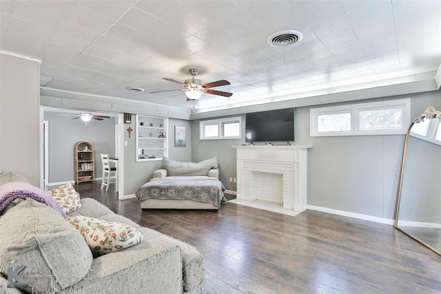 bedroom with baseboards, visible vents, ceiling fan, wood finished floors, and a fireplace