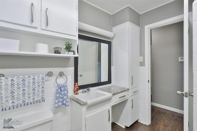 bathroom with baseboards, wood finished floors, vanity, and crown molding