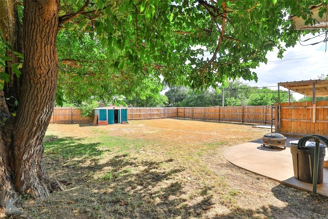 view of yard with an outdoor fire pit, a fenced backyard, an outbuilding, a storage unit, and a patio area