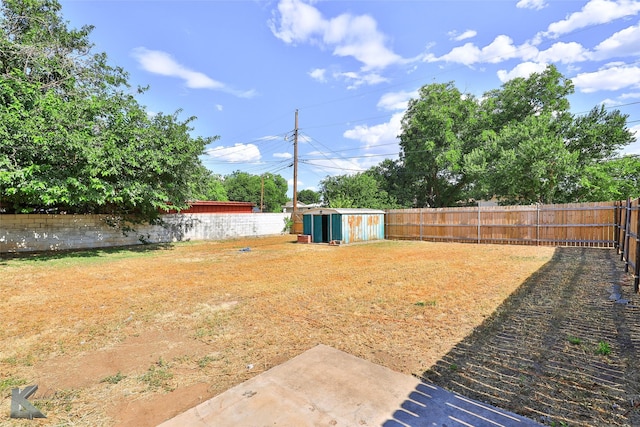 view of yard featuring an outbuilding, a storage shed, and a fenced backyard