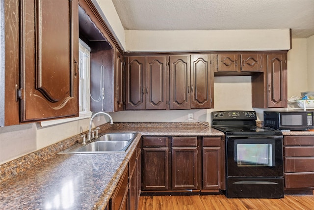 kitchen featuring light wood-style flooring, a textured ceiling, dark brown cabinets, black appliances, and a sink