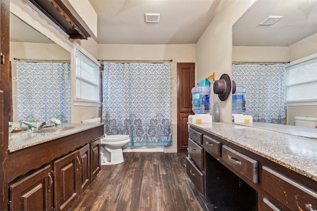 bathroom featuring toilet, visible vents, wood finished floors, and vanity