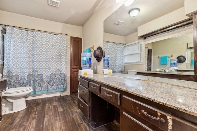 bathroom featuring toilet, vanity, wood finished floors, and visible vents