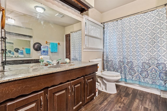 full bathroom featuring toilet, a shower with shower curtain, wood finished floors, vanity, and visible vents