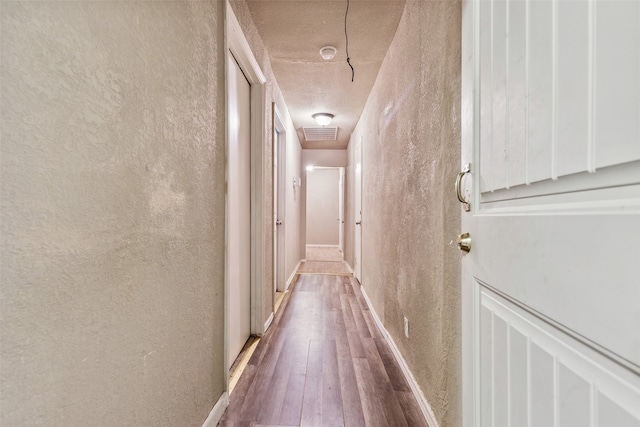 hallway featuring wood-type flooring and a textured wall