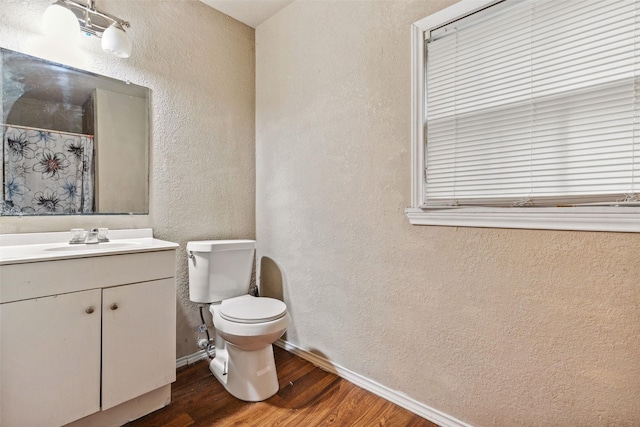 full bath with baseboards, a textured wall, toilet, wood finished floors, and vanity