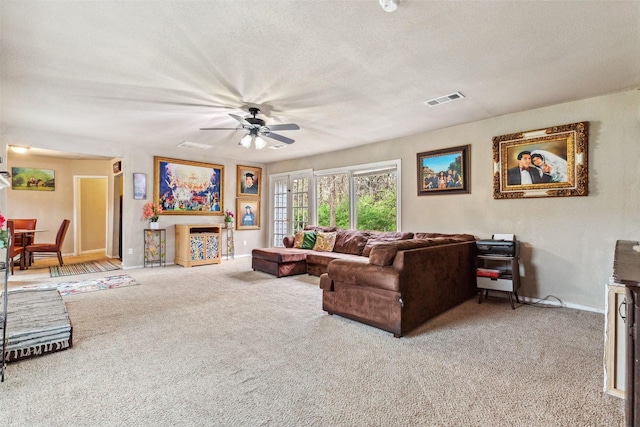 living area featuring a textured ceiling, carpet floors, visible vents, baseboards, and a ceiling fan