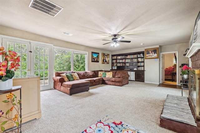 living room with a textured ceiling, carpet, a glass covered fireplace, and visible vents