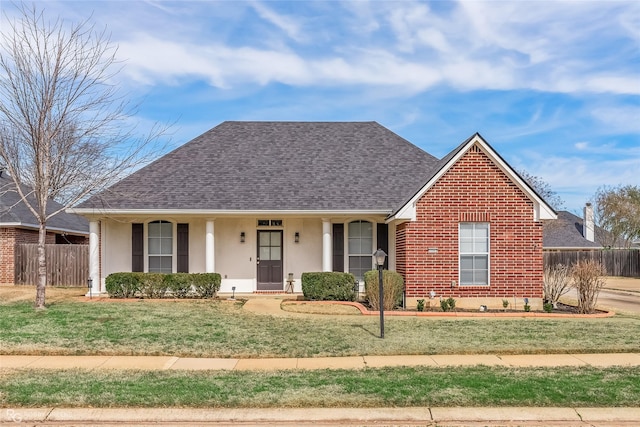 ranch-style home featuring brick siding, stucco siding, a shingled roof, fence, and a front lawn