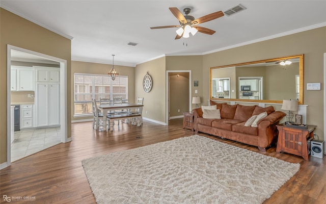 living area with crown molding, visible vents, wood finished floors, and ceiling fan with notable chandelier