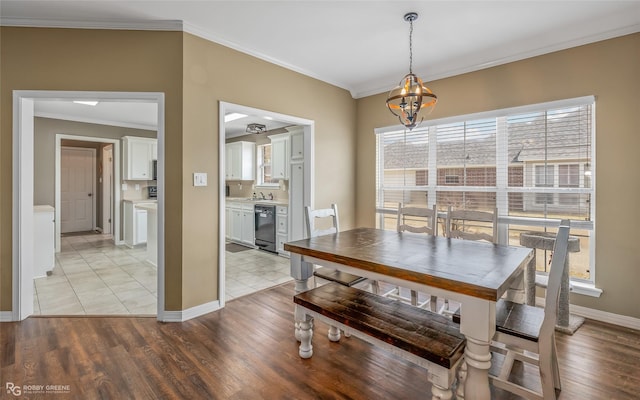 dining room featuring ornamental molding, an inviting chandelier, light wood-style flooring, and baseboards