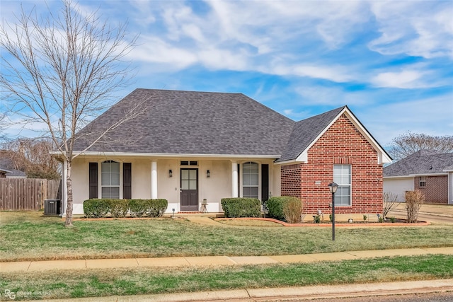 view of front facade with cooling unit, a shingled roof, brick siding, fence, and a front yard