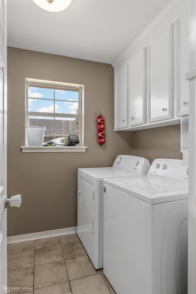 laundry area featuring light tile patterned flooring, washing machine and clothes dryer, cabinet space, and baseboards