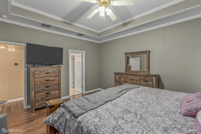 bedroom with visible vents, crown molding, baseboards, and wood finished floors