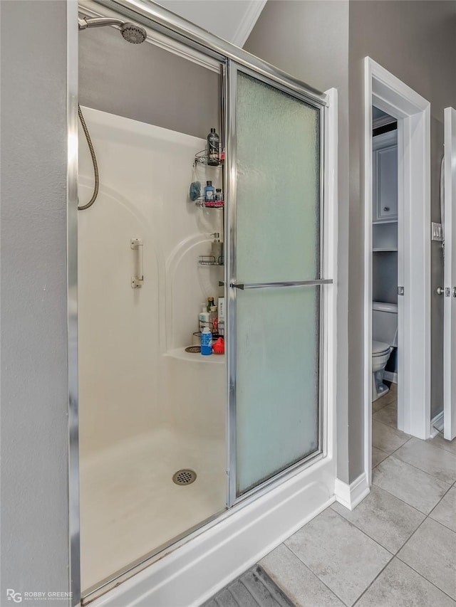 bathroom featuring toilet, a shower stall, and tile patterned floors