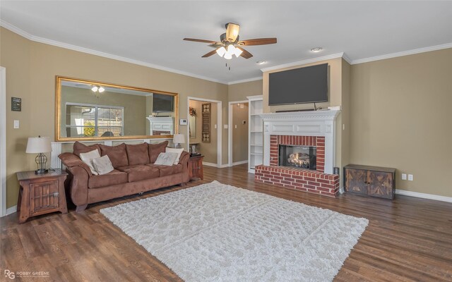 living area with crown molding, a brick fireplace, wood finished floors, and baseboards