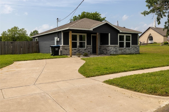 bungalow featuring fence, a shingled roof, and a front yard