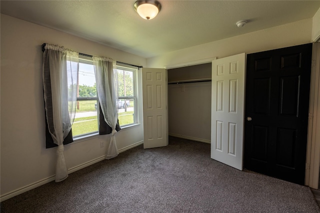 unfurnished bedroom with dark colored carpet, baseboards, and a closet