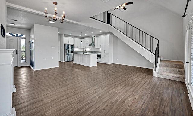 unfurnished living room with dark wood finished floors, recessed lighting, stairway, a sink, and baseboards