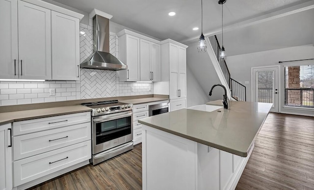 kitchen featuring dark wood finished floors, stainless steel electric range oven, tasteful backsplash, a sink, and wall chimney exhaust hood