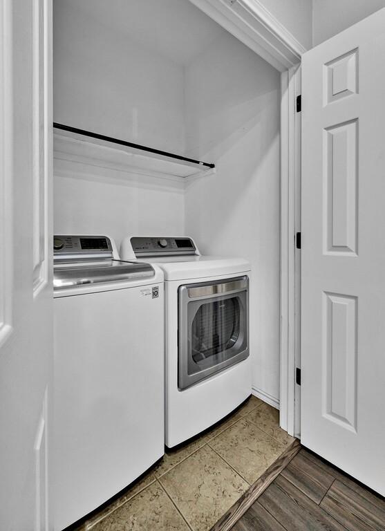 clothes washing area with dark wood-style floors, laundry area, and separate washer and dryer