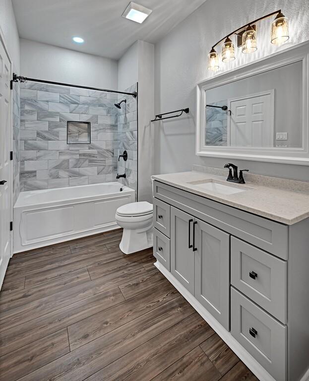 bathroom with toilet, vanity, shower / tub combination, and wood finished floors