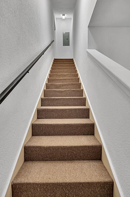 stairs with electric panel and a textured wall