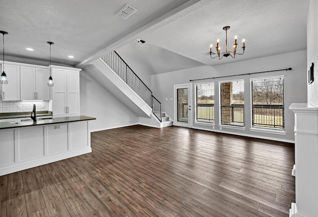 unfurnished living room featuring an inviting chandelier, visible vents, stairway, and dark wood-style flooring