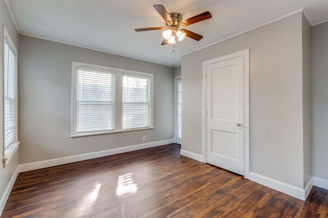 unfurnished bedroom with a ceiling fan, baseboards, dark wood finished floors, and crown molding