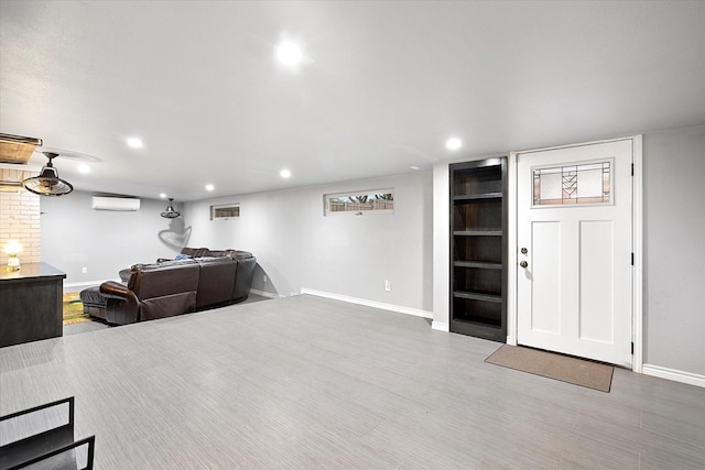 living area with baseboards, wood finished floors, an AC wall unit, and recessed lighting