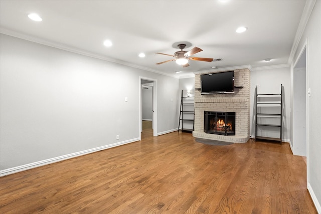 unfurnished living room featuring baseboards, a ceiling fan, ornamental molding, wood finished floors, and a fireplace