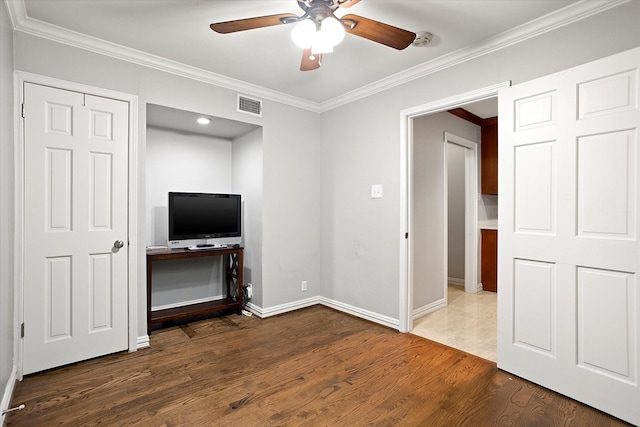 interior space with baseboards, visible vents, ceiling fan, wood finished floors, and crown molding